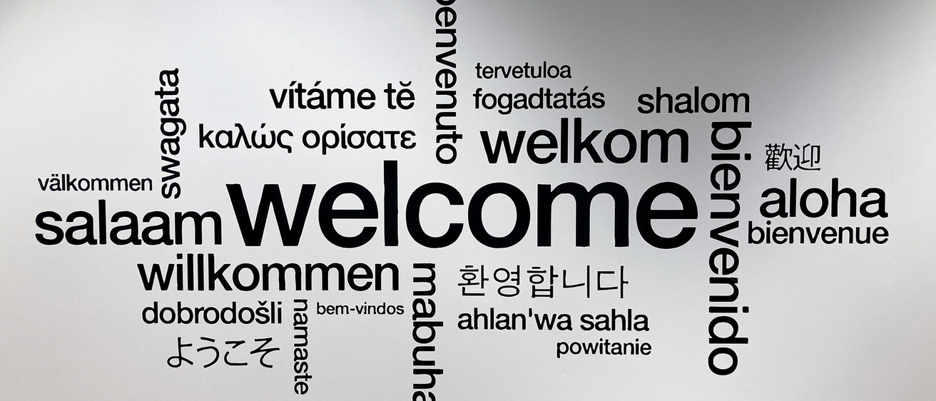 Entry wall of the Center for Language and Culture Learning, showing the word Welcome in various languages.